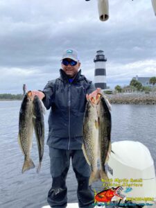 Fishing Guide Captain Keith Logan of North Myrtle Beach Fishing Charters with some nice speckled sea trout with light house in the back ground.