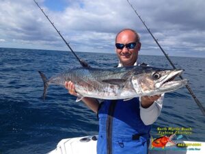 Captain Keith Logan holding a king mackerel on the the boat in the ocean on fishing charter in myrtle beach