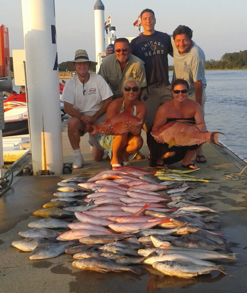 Deep Sea Fishing Charters In Myrtle Beach. People holdening fish and fish laying on the dock