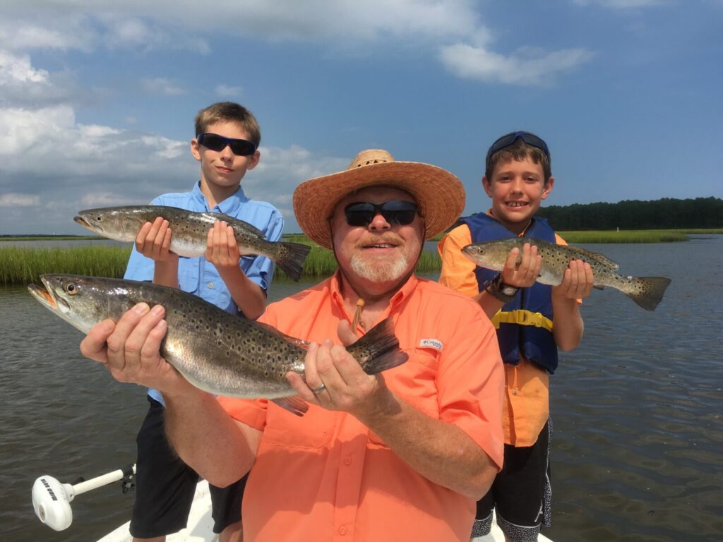 Inshore Fishing Charters In Myrtle Beach. Man and kids holding speckled sea trout.
