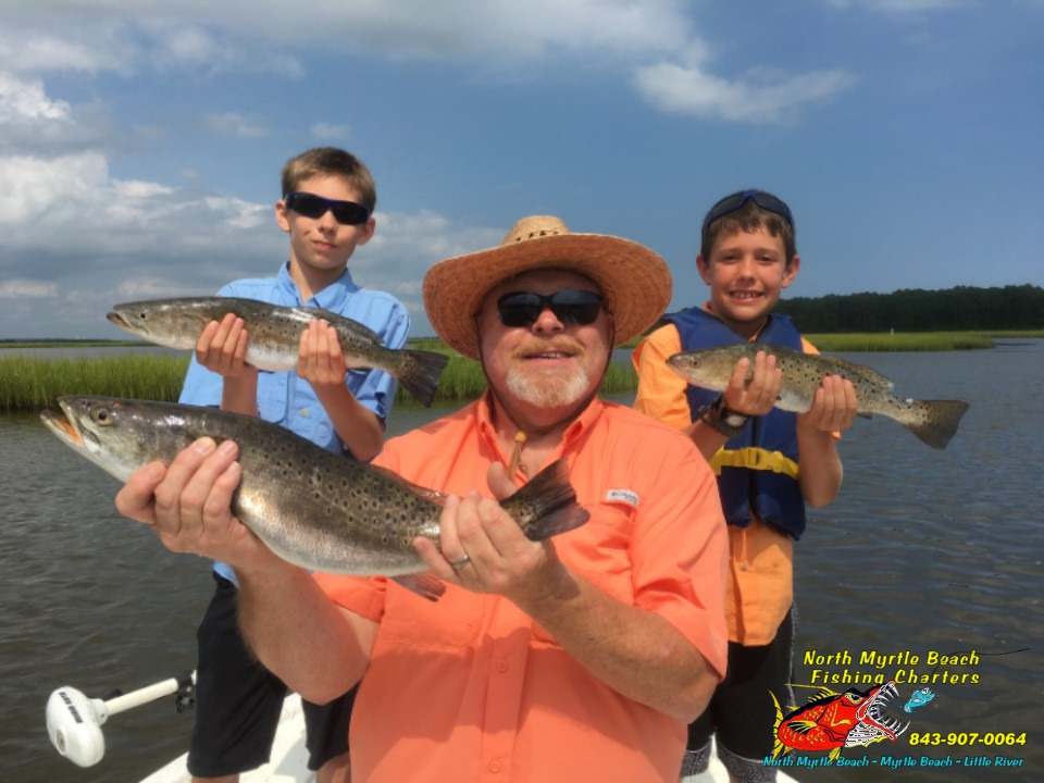 dad and two kids with three speckled sea trout on a Family Friendly Inshore Fishing Charters North Myrtle Beach 