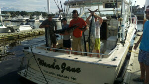 photo of a charter boat near me with people holding wahoo on the back of it with north myrtle beach fishing charters