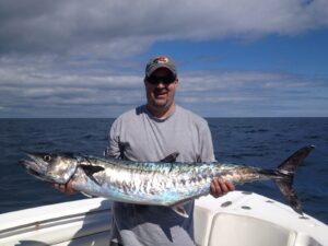 guy holding a king mackerel on a offshore charter with north myrtle beach fishing charters near me.