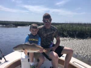 father and son holding a redfish on the bow of the for Spring Fishing Myrtle Beach with North Myrtle Beach Fishing Charters