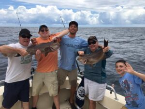 men standing on boat holding grouper on a Affordable Deep Sea Fishing Myrtle Beach charter