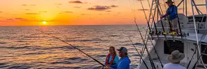 Deep sea fishing charter boat with anglers fishing at sunset