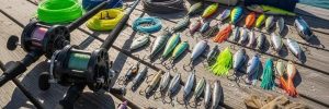 Variety of deep sea fishing tackle including rods, reels, and lures on a dock