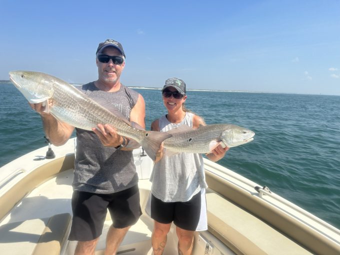 north-myrtle-beach-bull-redfish-fall Two anglers holding large bull red drum horizontally aboard a North Myrtle Beach fishing charter boat.