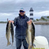 Fishing Guide Captain Keith Logan of North Myrtle Beach Fishing Charters with some nice speckled sea trout with light house in the back ground.