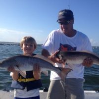 family holding two red drum aka redfish on a inshore fishing charters in north myrtle beach